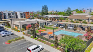 Aerial Exterior of leasing office and pool area, meticulous landscaping, grill area in enclosed pool area, bistro tables with umbrellas in pool area.