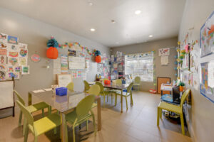 Interior Childrens Activity Room, two tables, white boards, children's toys, drawings on thee walls, tile floor.