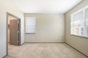 Interior Unit Bedroom, Gray molding, neutral toned walls and carpeting, windows on both walls, walk-in closet.